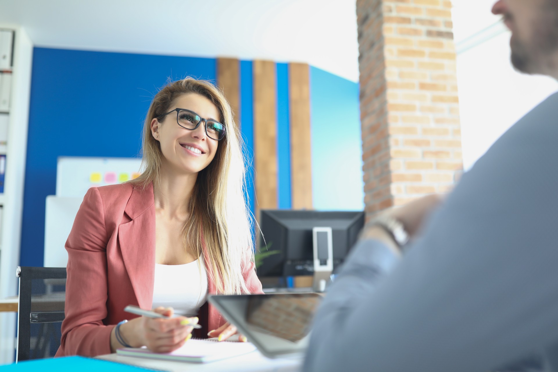 Business woman with glasses sitting at table and conducting interview with man