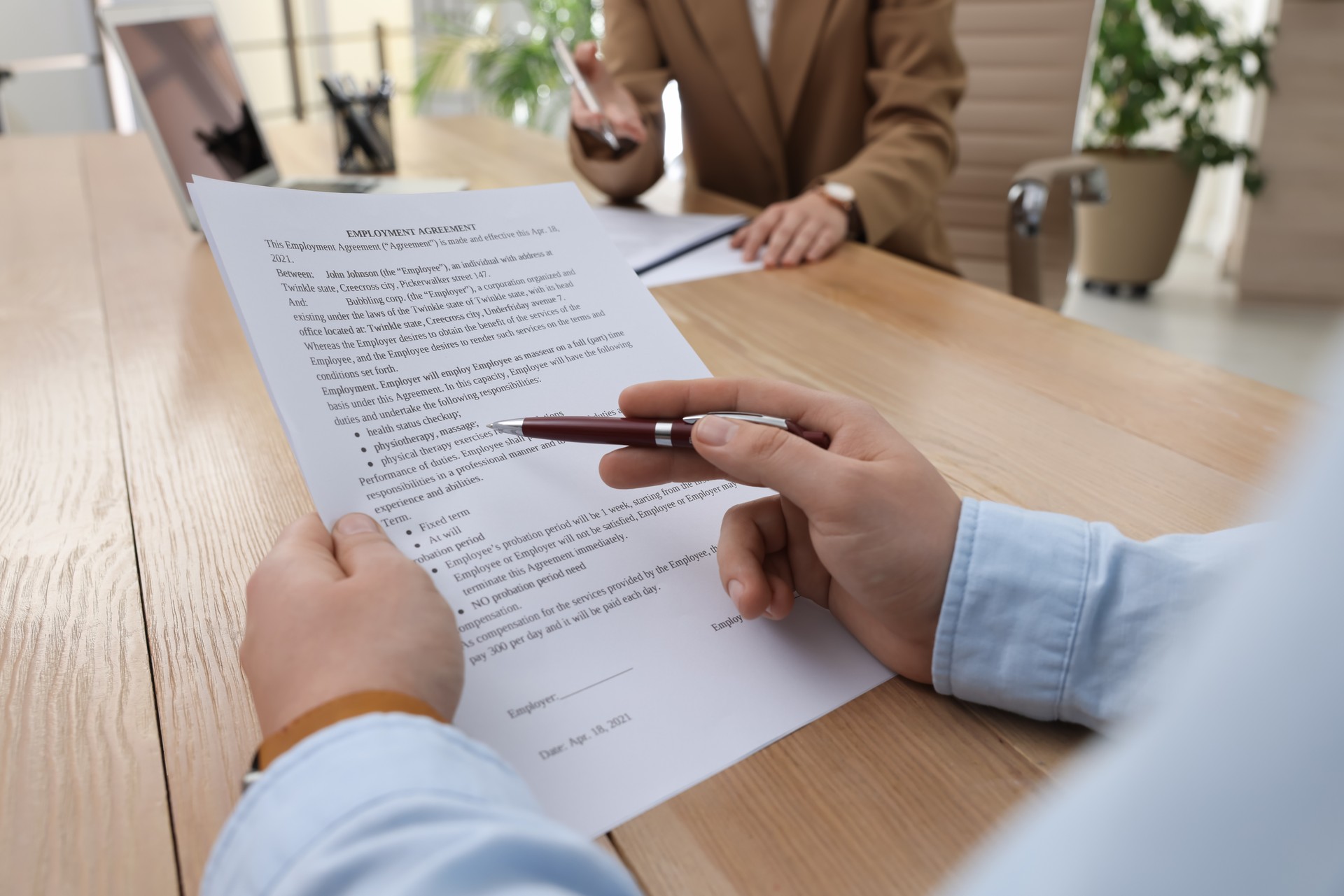 Man reading employment agreement at table in office, closeup. Signing contract