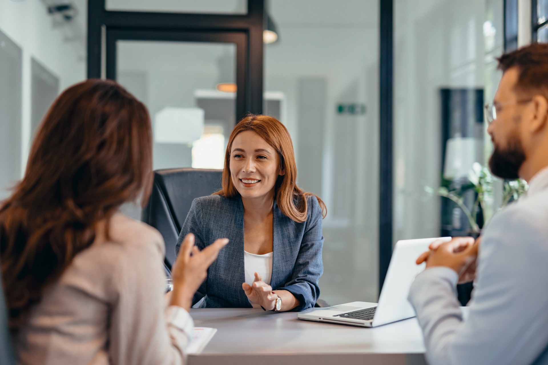 Three professionals in a discussion at an office meeting setting.